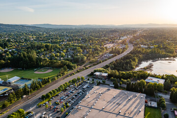 4K aerial photo of Tualatin Valley Highway in Beaverton, Oregon, heading west at sunset. Scenic view includes tennis courts, baseball fields, distant neighborhoods, and surrounding nature © Hrach