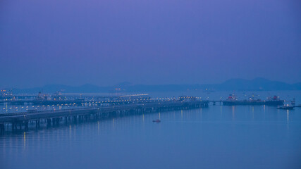 Obraz premium Logistic shipping quay boat in twilight sky night Engineering crane depot at logistic export terminal control. Warehouse freight background container yard loading quayside harbor port Logistics.