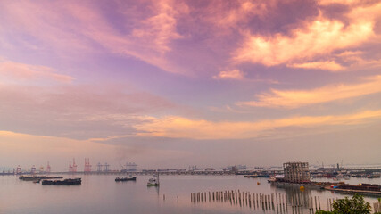 Logistic shipping quay boat in twilight sky night Engineering crane depot at logistic export terminal control. Warehouse freight background container yard loading quayside harbor port Logistics.