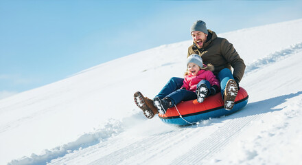 Father and daughter sledding downhill on snow tube in winter landscape. Thrilling family adventure, memorable bonding experience during cold season Father's Day celebration