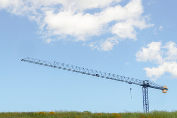 Construction crane standing tall against a blue sky with fluffy white clouds, symbolizing growth...
