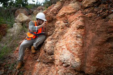 A geologist is using a steel rod to drill into a rock to obtain a rock sample for analysis