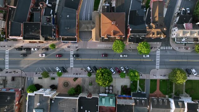 Traffic jam on main Street of small american town in Ephrata. Aerial top down rising shot. Green trees in spring. Roof top of row houses at sunset. Pennsylvania in United Stares.
