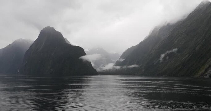 Scenic cruising at Milford Sound (Piopiotahi), Fiordland National Park on the South Island of New Zealand. Milford Sound surrounded by looming mountains and impressive sheer rock faces.