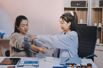 Fototapeta premium Doctor using sphygmomanometer with stethoscope checking blood pressure to a patient in the hospital.