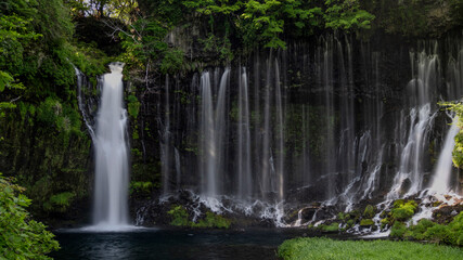 Breathtaking view of Shiraito no Taki waterfalls cascading down a lush, moss-covered cliff into a tranquil pool below.
