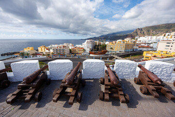 Old artillery pieces aligned on a fortress terrace overlooking the sea and urban skyline, with...