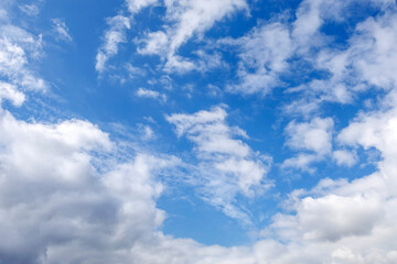 Dynamic cloudscape with soft white cumulus clouds drifting across a vivid blue sky, ideal as background or atmospheric element