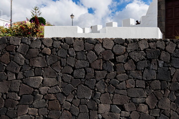 Close-up and frontal view of a rustic basalt stone wall with rough texture and organic pattern,...