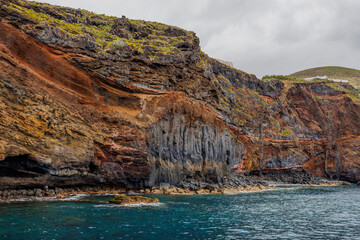 Dramatic geological formations along a rugged coastline with ocean views, showing volcanic layers, erosion textures and natural detail.