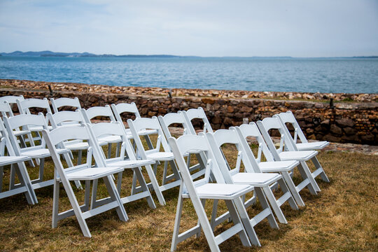 White chairs set up beside ocean for wedding
