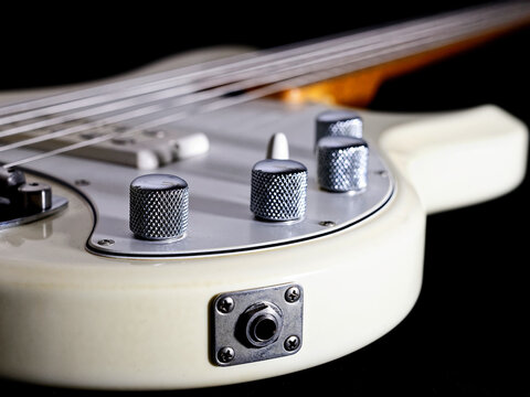 Cream white electric bass guitar showing strings side view