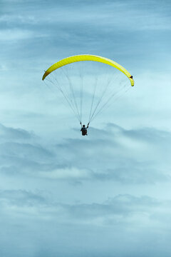 Yellow paraglider in a cloudy and moody sky