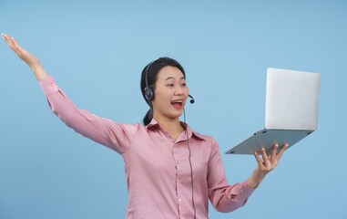 Young woman in headset happily presenting information during an online meeting against a blue...