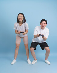 Young Asian friends enjoying a video game together in a bright, playful studio setting with a light...