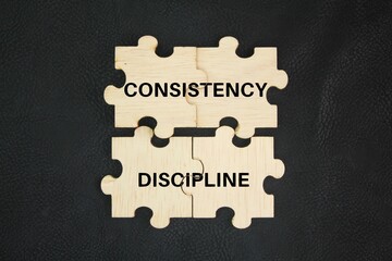 Wooden puzzle with the words consistency and discipline. concept. interconnected concepts, both essential for achieving goals and building lasting habits.