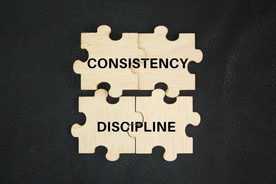 Wooden puzzle with the words consistency and discipline. concept. interconnected concepts, both essential for achieving goals and building lasting habits.