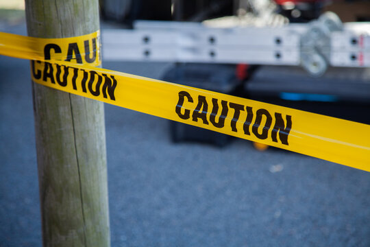 Caution tape around a post with ladder behind