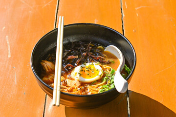 Photo of Curry Ramen with Tori in the black bowl. close up view, above, high angle. Chopsticks, white spoon.
