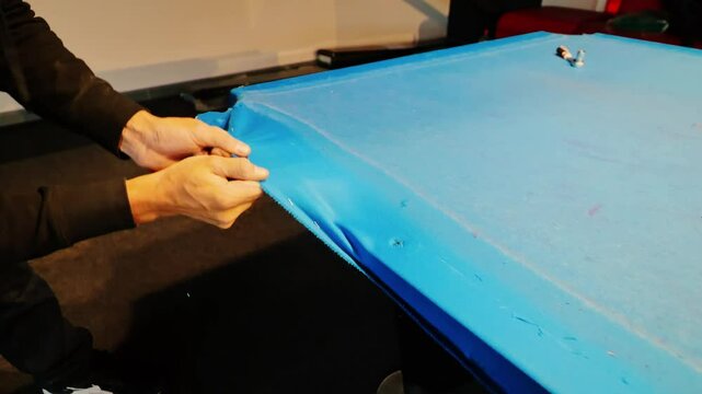 Restoration of worn billiard table as blue felt is carefully removed by hand, 4k