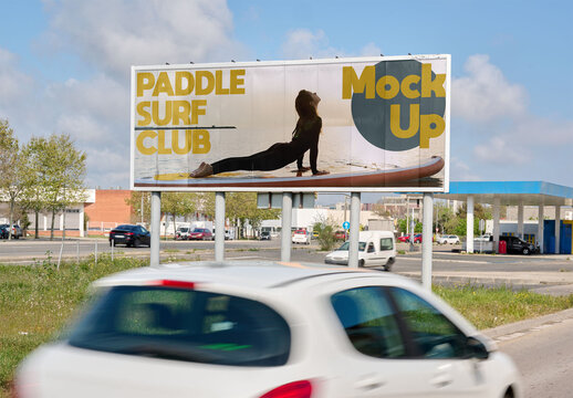 Empty billboard mockup stands alongside bustling traffic.