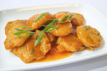 Close-Up of Spicy Fried Nuggets with Sauce and Green Onion Garnish