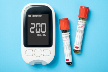 Tube with a blood sample and a glucometer with the glucose level on the screen. Concept of diabetes...