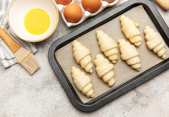 Baker preparing raw croissants on baking tray for baking