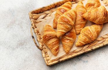 Freshly baked croissants resting on a wicker tray, a delightful breakfast scene
