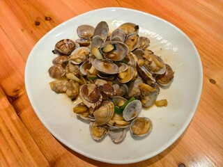Fototapeta premium Cooked clams served on a white plate over a wooden table