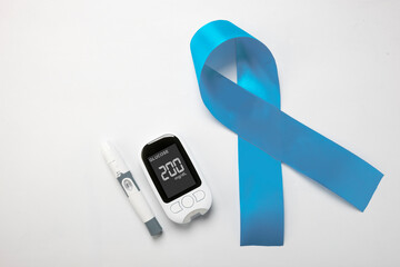Lancet and a glucometer with the glucose level on the screen with a blue ribbon awareness on a...