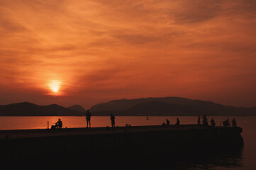 Obraz premium Silhouettes of several fishermen fishing on the pier at dawn.