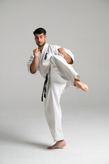 Kyokushinkai karate fighter kicking high in studio setting