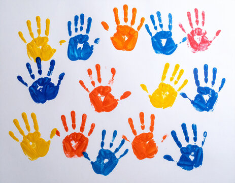 Colorful handprints are painted on a large sheet of white paper, symbolizing collaborative creativity and art. - Powered by Adobe