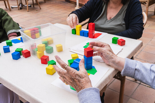 Senior women engaging in recreational activities with colorful building blocks at an outdoor nursing home setting, promoting cognitive stimulation and social interaction