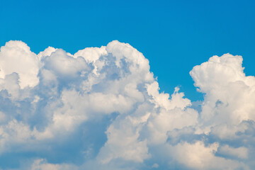 Naklejka premium Fluffy white clouds against clear blue sky on a sunny day