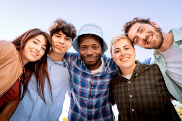 Happy group of young multiracial friends smiling and looking at camera outdoors