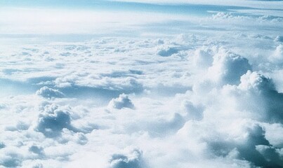 An aerial view of a vast expanse of fluffy white and light blue cumulus clouds under a bright sky