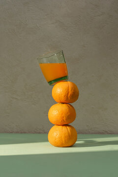 An artistic display of stacked oranges supporting a glass of juice