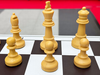 Close-up of chess pieces on a black and white board: king, queen, bishop, pawns