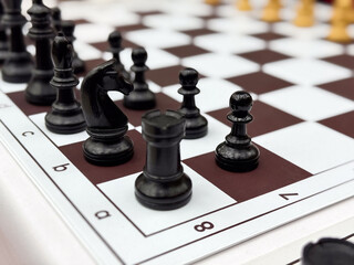 Close-up of black chess pieces on a chessboard in mid-game position