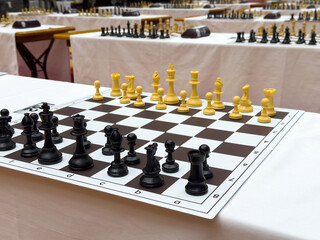Chess tournament setup with white and black pieces on wooden tables