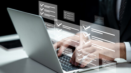Businessman using a laptop while showing a questionnaire with a checkmark icon. Tablet on the table. Technology innovation on a virtual screen. Concept of online exam questionnaire