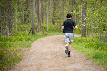 Fototapeta premium Man Jogging Through A Forest On A Peaceful Summer Day