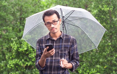 man holding umbrella and smartphone with green background