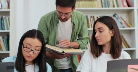 Students team study together using laptop prepare for exam in library, multiethnic young people group talk looking at computer. Education concept. - Powered by Adobe