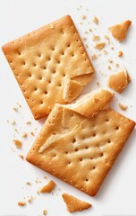 Two square crackers, broken apart, showing crispy texture.  Crumbs scattered around