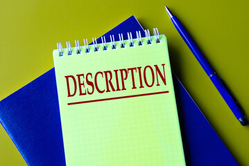 DESCRIPTION - word in yellow notebook on blue notebook and pen background