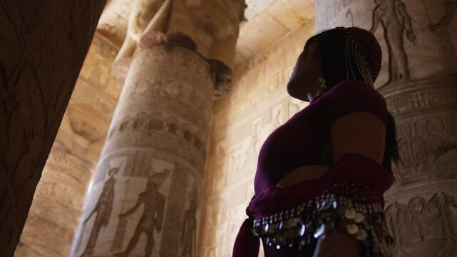 Woman admiring ancient temple art in Dendera, Egypt, surrounded by carved columns