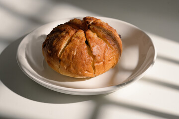 golden-brown loaf of bread on a white plate in natural light